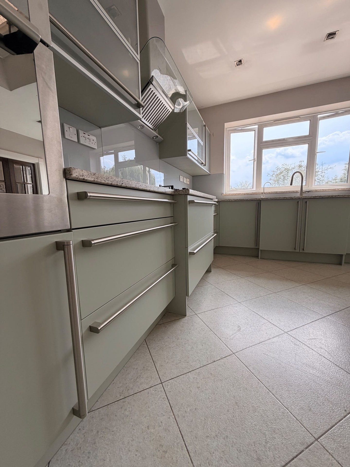 Sage green handleless kitchen respray with stainless steel bar handles and granite worktop